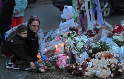 Una madre lleva flores a un altar improvisado en Newtown, Connecticut en memoria de las 26 personas que perdieron la vida en una masacre.