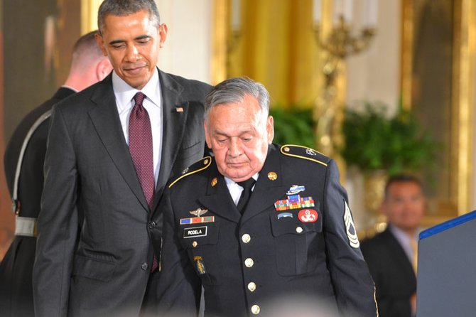 El presidente ayudando a subir al podium a José Rodela, el tercer veterano sobreviviente de los 24 que fueron reconocidos el martes 18 en la Casa Blanca.