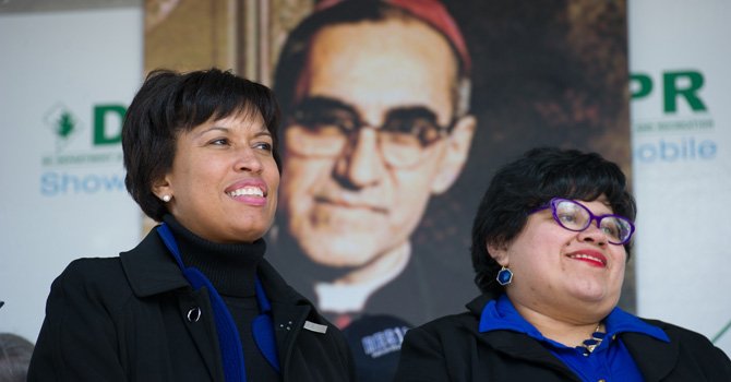 La alcaldesa de DC, Muriel Bowser (izq.) junto a la directora de la Oficina de la Alcaldesa para Asuntos Latinos (OLA), Jackie Reyes, el sábado 21 de marzo, durante la dedicatoria de un edificio de la Mount Pleasant al arzobispo salvadoreño Oscar Romero.