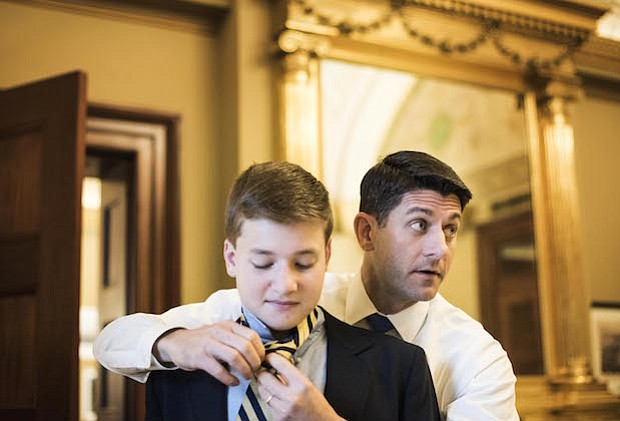 Mientras se reúne con su personal, el presidente de la Cámara de Representantes Paul Ryan, R-Wis., hace la corbata para su hijo de 13 años, Charlie, antes de las ceremonias de juramento en la Cámara en el primer día del 115 Congreso.
