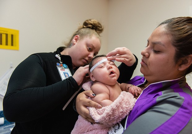 Jessica Rios sostiene a su sobrina Aryanna Guadalupe Sánchez-Ríos mientras un técnico que mide el cráneo del bebé en el Hospital de Niños de Seattle el 5 de mayo de 2017. A los 3 meses de edad, su cabeza era todavía más pequeña que la media.