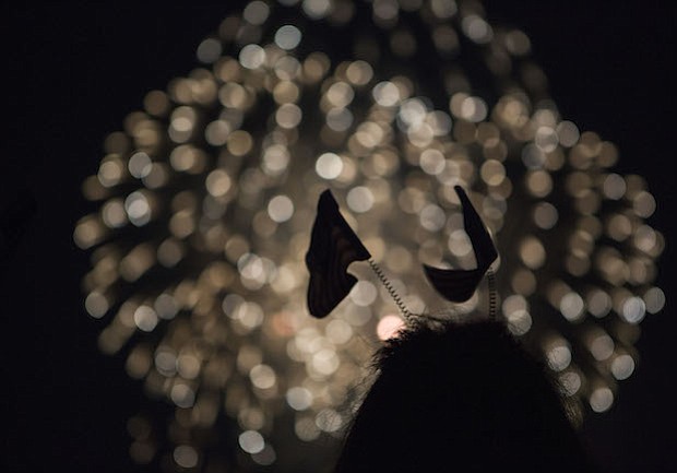 Una mujer joven en una venda de la bandera mira los fuegos artificiales en el monumento de Washington en Washington, D.C.