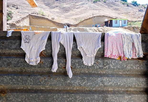 La ropa de bebé se seca en el refugio Camino de Salvación, que es el hogar de familias con niños. El refugio está ubicado a unos 20 minutos de la frontera, en el barrio El Pipila de Tijuana, al final de un largo camino de tierra. El acceso a agua y electricidad es limitado. Todos los migrantes comparten dos baños, cada uno con algunas casetas. (Heidi de Marco/KHN)
