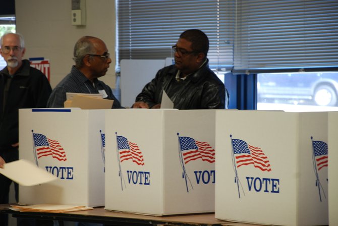 El oficial electoral Luis Marrero (izq.) ayuda a Evaristo Rosales, recién naturalizado, en su primera votación el martes 6. Crédito: ETL