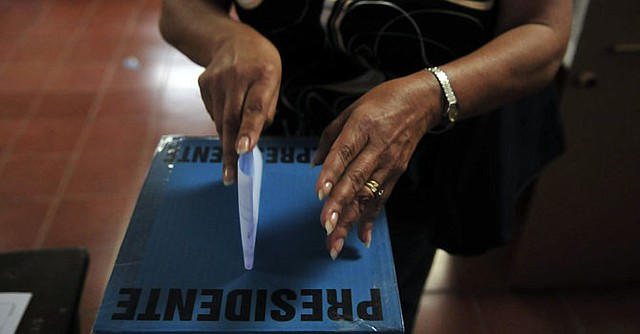 Una mujer deposita su voto en unas elecciones presidenciales en El Salvador