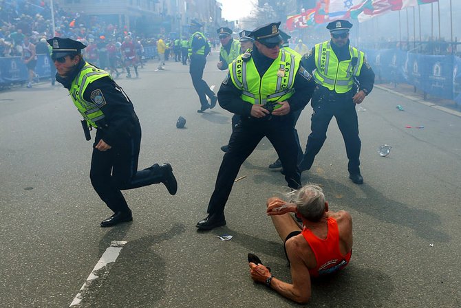 Policías frente a un maratonista que cayó al suelo al estallar una de las bombas.