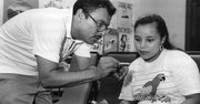 PIONERO. El doctor Juan Romagoza, quien dirigió la clínica por dos décadas desde 1988 hasta 2008, asiste a una paciente en el antiguo local.