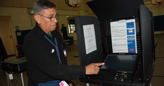 El oficial electoral Wiston Martínez, de Bolivia muestra la computadora para emitir el voto digital.