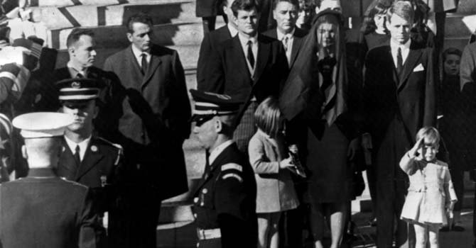 El joven John F. Kennedy Jr. (d), de tres años de edad, saluda al paso del féretro que contiene los restos mortales de su padre, el presidente de los Estados Unidos John F. Kennedy, durante su traslado desde la catedral de San Mateo hasta el cementerio nacional de Arlington. También aparecen en la imagen, Edward Kennedy (c); la hija del presidente, Caroline Kennedy; el actor Peter Lawford; Jacqueline Kennedy y el fiscal general, Robert Kennedy.