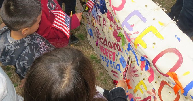 Un grupo de niños lee uno de los letreros sobre la unidad familiar frente a las deportaciones en la marcha del 5 de abril.