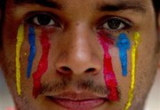 Un estudiante universitario con el rostro pintado con rayas que simulan lágrimas con los colores de la bandera de Venezuela mira a la cámara durante una manifestación antigubernamental en Caracas, Venezuela, el sábado 12 de abril de 2014. (Foto AP/Fernando Llano)
