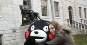 Fotografía de archivo del 12 de noviembre de 2013 de Kumamon, tal vez el más exitoso de los nuevos personajes creados para promover una ciudad en Japón, mientras recibe un abrazo de la argentina Mariel Cerra frente a una estatua de John Harvard en el campus de la Universidad de Harvard en Cambridge, Massachusetts. (Foto AP/Steven Senne, Archivo)