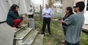 Sosteniendo un cable quemado que afectó a su trailer Ojilvia Moreno Solano (izquierda) y sus familiares Nieves Moreno Solano y Rufino Cano Vázquez conversan con el abogado que los representa Phil Storey (centro) del Legal Aid Justice Center de Richmond, Virginia.