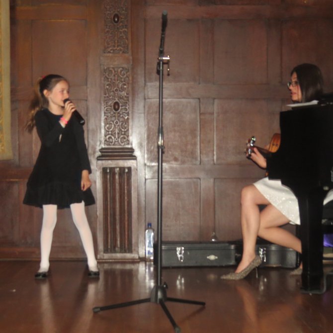 Una estudiante muestra con su canto su aprendizaje del español acompañada por Narda Muñoz.