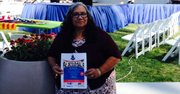 La coordinadora Bethzaida Cordero McGuire sostiene un volante de la Expo New Americans, durante su visita al VietFest 2015 en Tysons Corner Mall, Virginia.