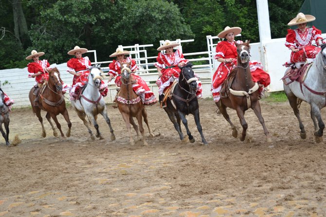 Las Amazonas del Dorado, realizando una de sus acrobacias sobre sus caballos.