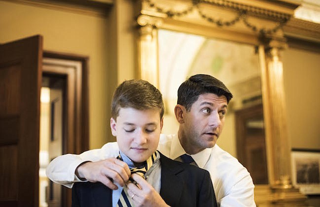 Mientras se reúne con su personal, el presidente de la Cámara de Representantes Paul Ryan, R-Wis., hace la corbata para su hijo de 13 años, Charlie, antes de las ceremonias de juramento en la Cámara en el primer día del 115 Congreso.