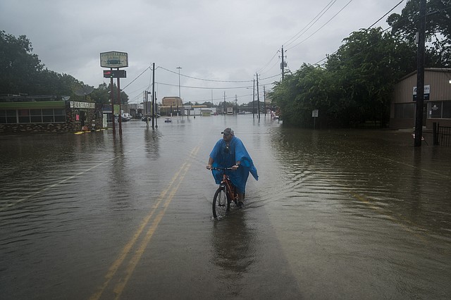 Un hombre monta su bicicleta a lo largo de Mercury Drive en Houston durante la tormenta tropical Harvey.