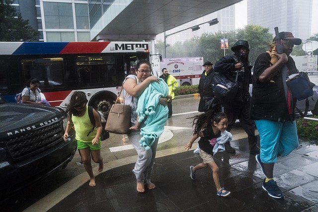 Las personas rescatadas salen de los autobuses hacia el Centro de Convenciones George R. Brown de Houston.