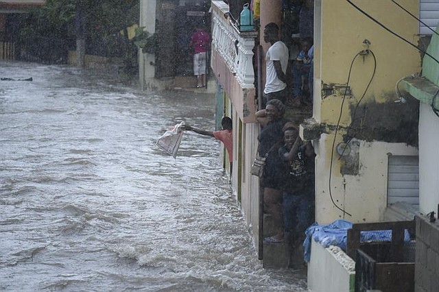 Personas observan una calle inundada el 7 de septiembre, en Santiago de los Caballeros, República Dominicana. Lluvias y vientos desde las 3:00 a.m. de este día inundaron la calle 4B y 11 del sector Hoya del Caimito, donde al menos 150 casas quedaron inundadas por la crecida del arroyo que cruza por esta barriada. Más de 5.500 personas han sido evacuadas en República Dominicana a causa del poderoso huracán Irma.
