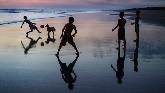 Niños se divierten jugando en la orilla de la playa al atardecer.