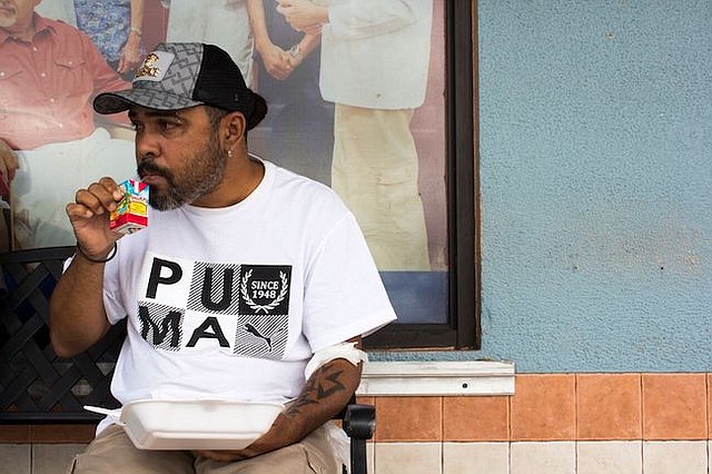 García toma un jugo fuera del Fresenius Kidney Care en Humacao, Puerto Rico, después de recibir diálisis. Su comida, que provee Renal Council, una organización local sin fines de lucro, incluye arroz, carne roja y vegetales.