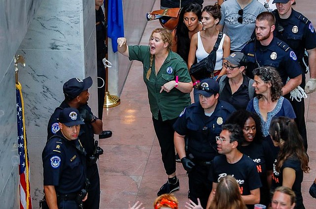 La comediante estadounidense Amy Schumer (c) gesticula después de ser detenida junto con cientos de otros manifestantes en el atrio del edificio de la oficina del Senado de Hart en Washington