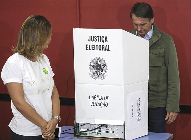 BRASIL. El candidato de derecha del Partido Social Liberal (PSL) Jair Bolsonaro (R) y su esposa Michelle (L) votan en una mesa electoral en Río de Janeiro