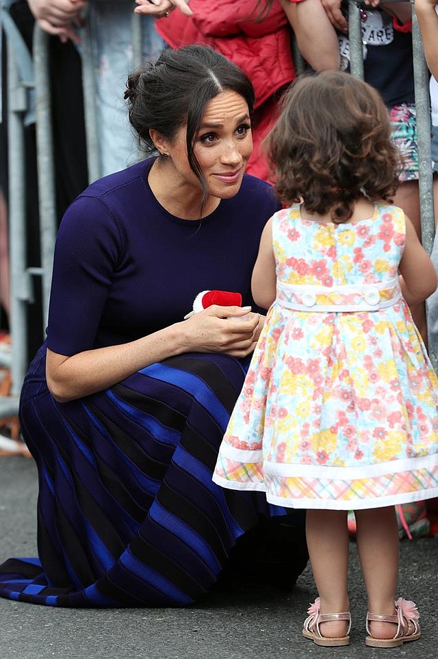 NUEVA ZELANDA. La duquesa Meghan de Sussex (i) saluda a una niña durante una visita a los jardines de Rotorua