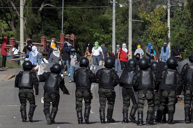 REPRESIÓN. Estudiantes universitarios con sus rostros cubiertos se enfrentan policías militares del Orden Público en Tegucigalpa.