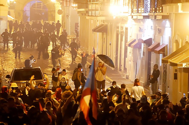 DISGUSTO. Miembros de la policía dispersan a manifestantes el lunes, 22 de julio, en San Juan. Lanzaron gases lacrimógenos contra manifestantes frente a La Fortaleza, sede del ejecutivo. | Foto Efe/Thais Llorca