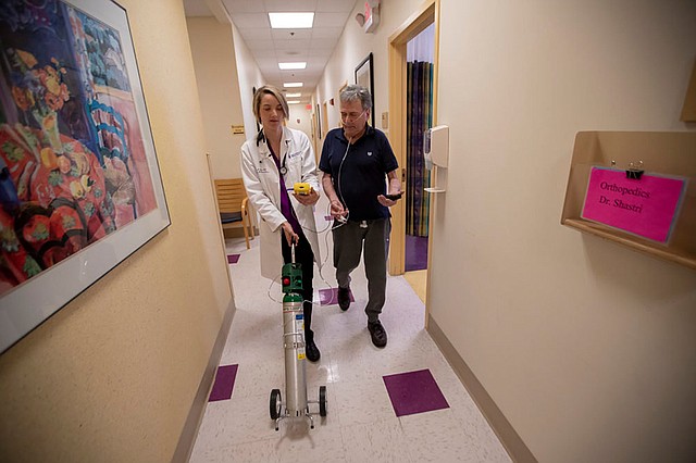 La doctora Mary Rice acompaña a Michael Howard en la Beth Israel Deaconess HealthCare Clinic en Chelsea, Massachussetts, mientras Howard prueba los niveles de oxígeno agregados en su tanque de oxígeno portátil. Howard tiene enfermedad pulmonar obstructiva crónica (EPOC), una condición progresiva de los pulmones que puede agravarse con el calor y la humedad. (Jesse Costa/WBUR)