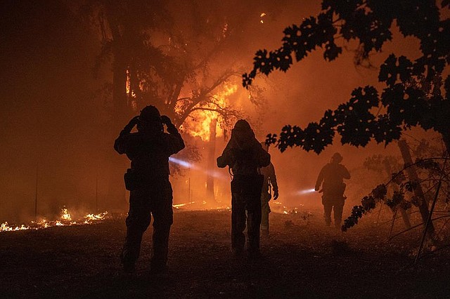 CRISIS. Un bombero evalúa un edificio que se quema sin control mientras el incendio de Kincade sigue ardiendo en Healdsburg, California, EE.UU.