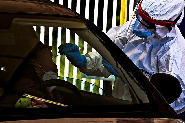 MUNDO. Un trabajador sanitario que lleva un mono y una máscara protectora realiza una prueba de hisopado a un automovilista sentado en su coche en Pozzuoli, cerca de Nápoles, Italia, 16 de abril de 2020