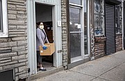 Angélica, quien se aisló luego de salir positivo en la prueba de COVID-19, recoge la caja de comida de Centro Presente en la entrada de su casa. (Robin Lubbock/WBUR)