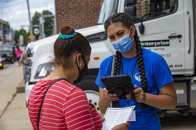 Con una tableta, la voluntaria de Chelsea Collaborative, Yudalys Escobar, ayuda a un residente de Chelsea a completar el censo de 2020 durante un evento de distribución de alimentos en 6th Street.