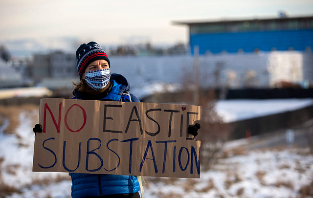 Juliane Manitz de Chelsea en una protesta contra la subestación eléctrica de East Boston. La ubicación propuesta es el área cercada y cubierta de nieve que se encuentra detrás de ella.